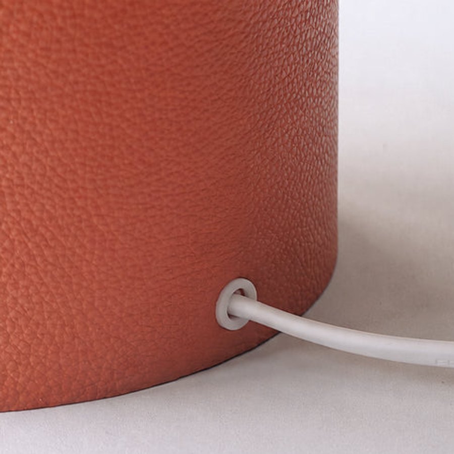 A wrapped lamp base with its power cord, beside the printed shade