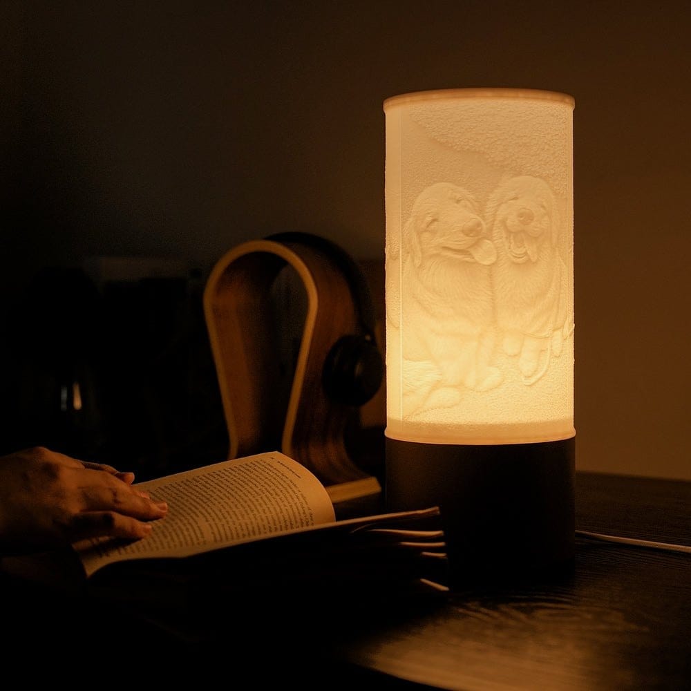 A Column photo lamp glowing with a portrait of two dogs, on a desk at night